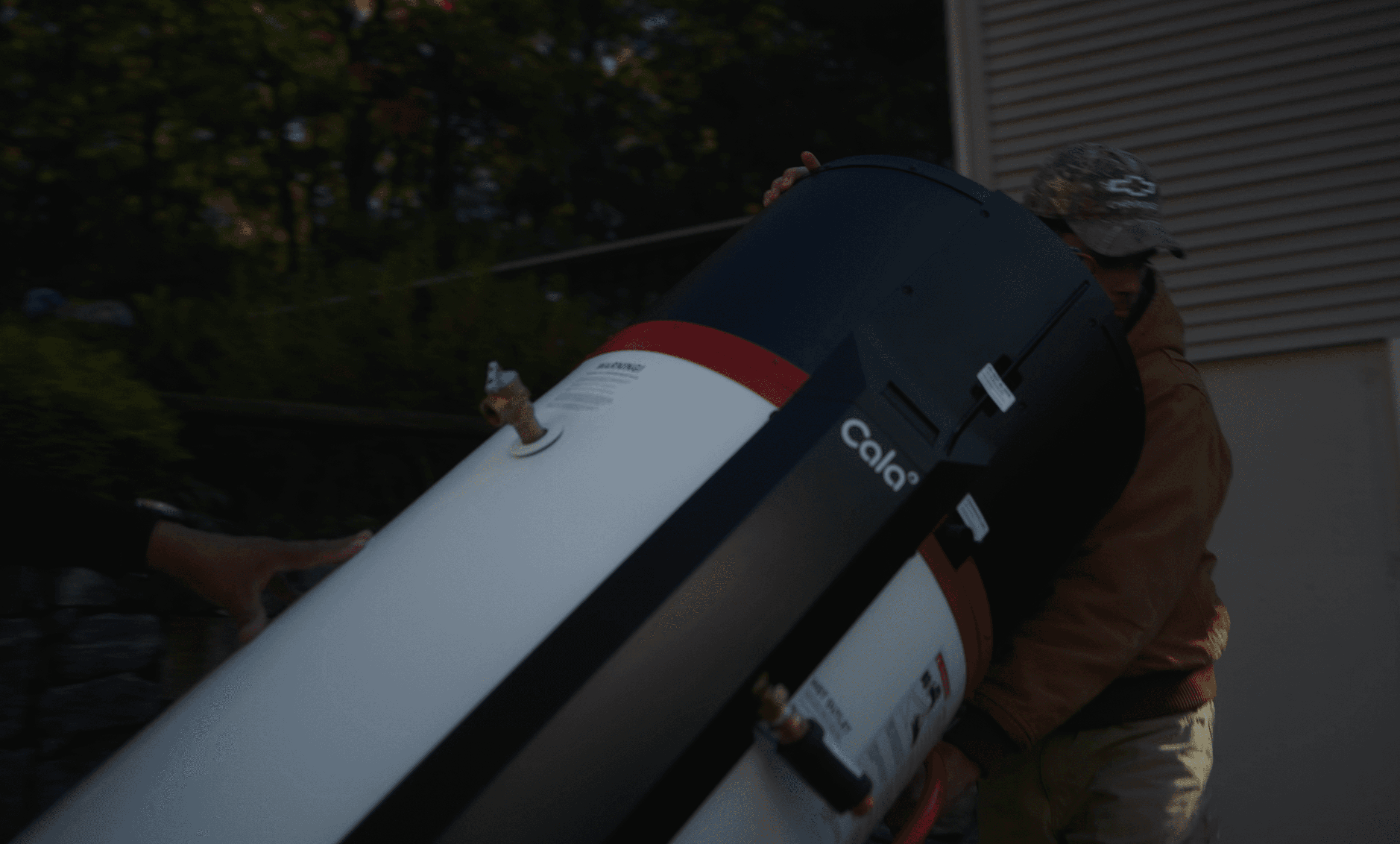A SumZero technician tilting the unboxed Cala unit to carry it toward the house.