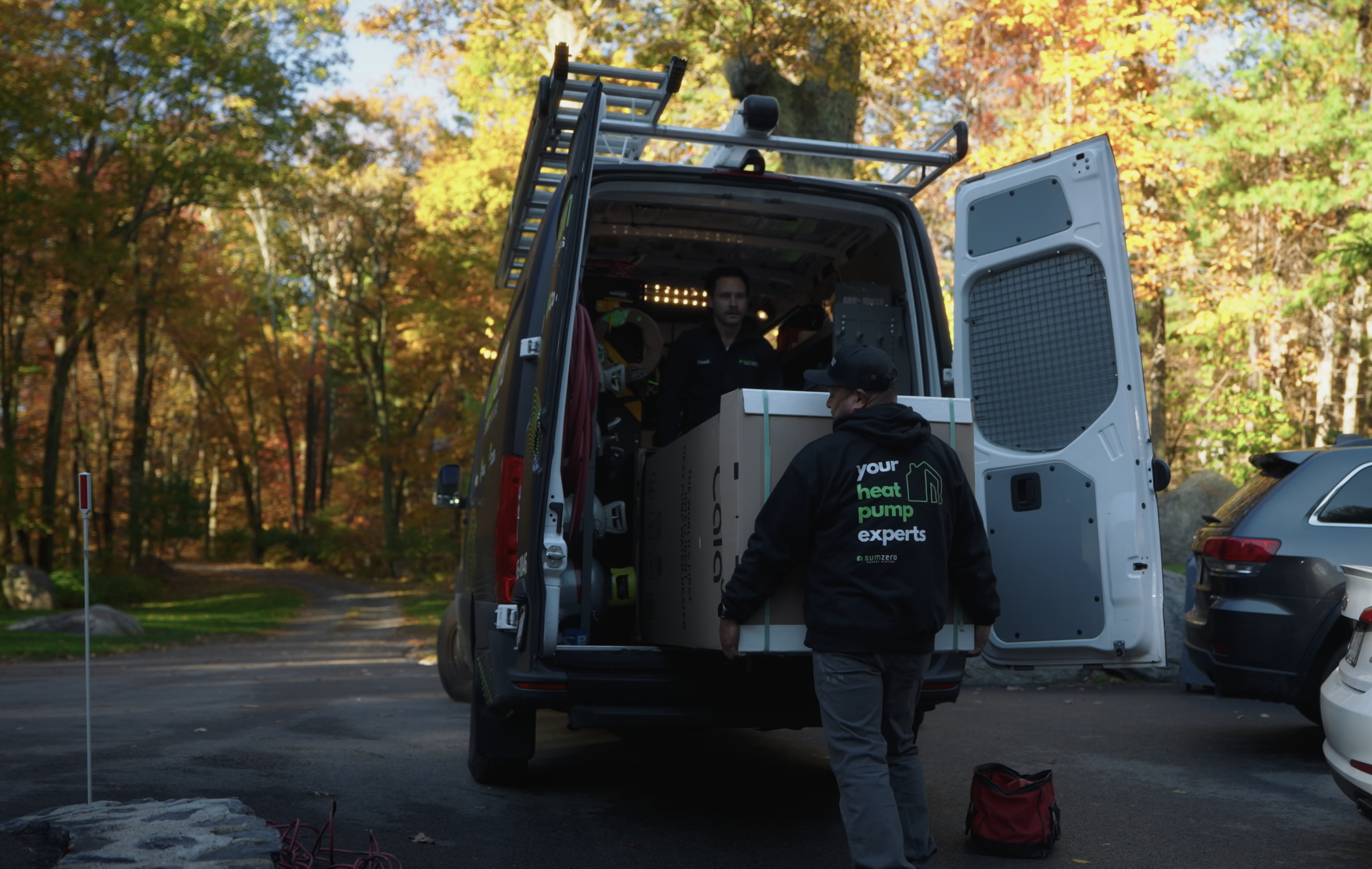 The SumZero crew unloading a boxed Cala from their van on an autumn driveway.