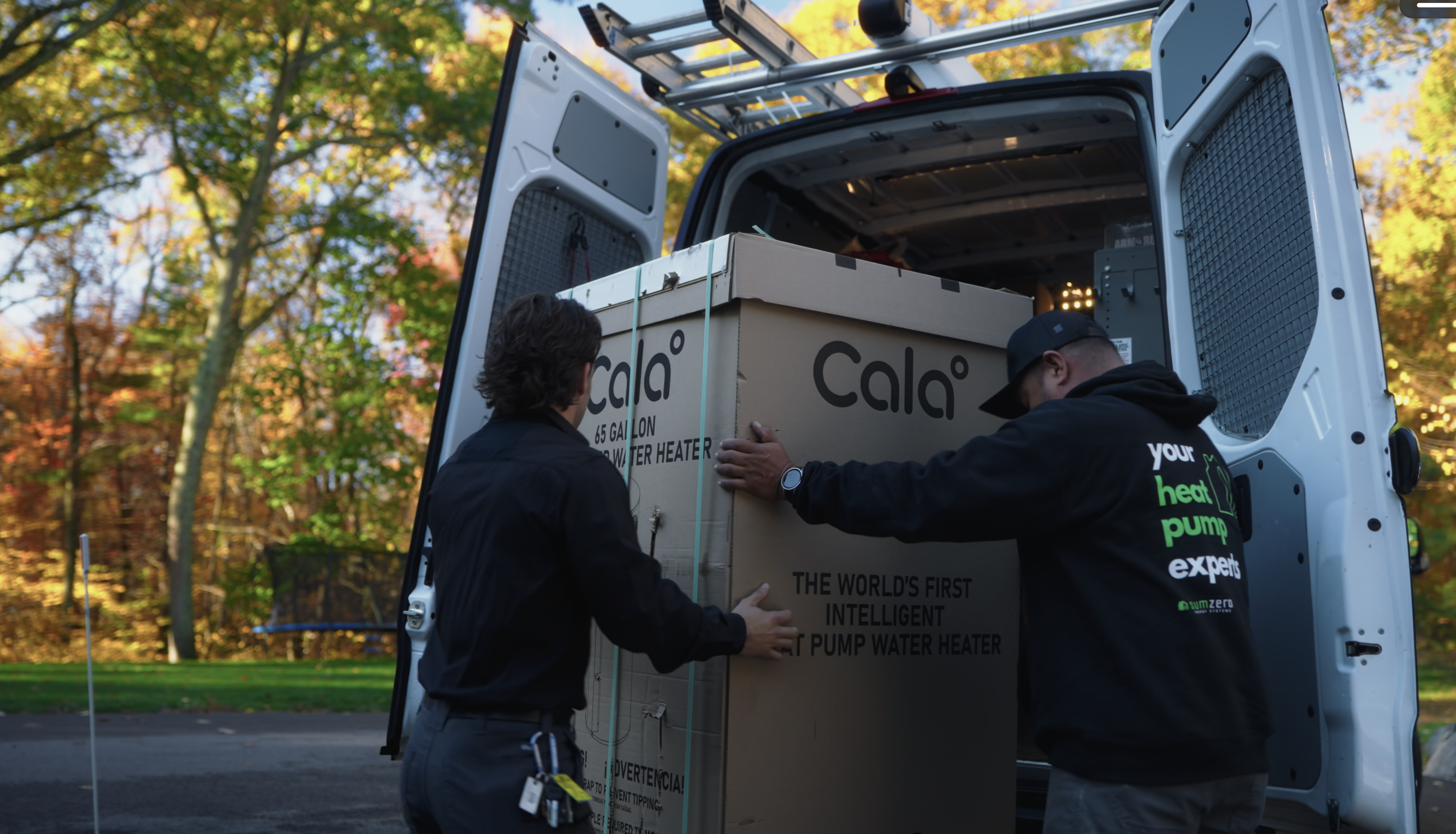 Two SumZero technicians lifting a sealed Cala box out of the back of the van.